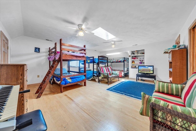 bedroom featuring lofted ceiling with skylight, a ceiling fan, and wood-type flooring