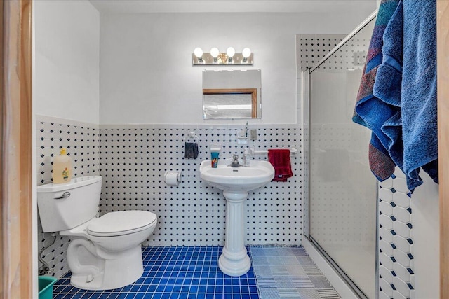 full bath with tile patterned flooring, toilet, wainscoting, a stall shower, and tile walls