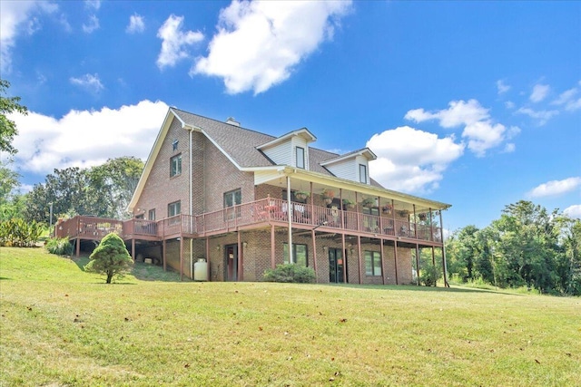 back of property featuring a deck, a lawn, and brick siding