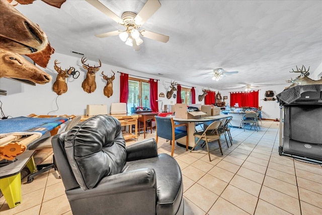 living room featuring light tile patterned floors, visible vents, and ceiling fan