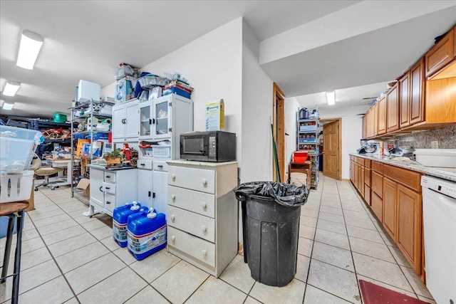 kitchen with backsplash, light tile patterned flooring, white dishwasher, black microwave, and light countertops