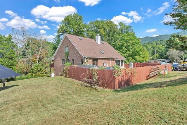 back of property featuring a lawn, a chimney, and fence