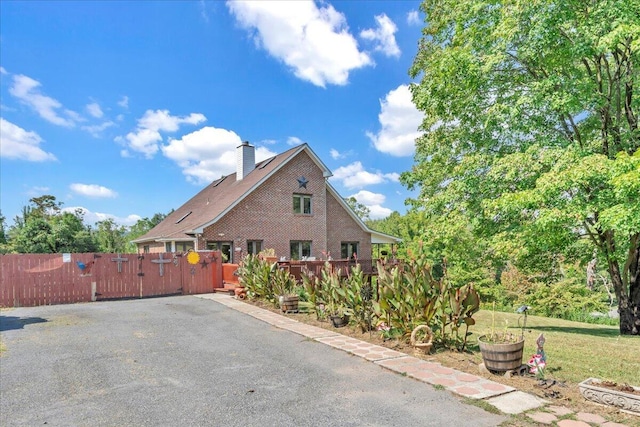 view of side of property with a gate, fence, and a chimney