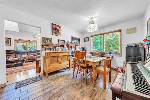 dining area featuring baseboards, hardwood / wood-style floors, and ceiling fan with notable chandelier