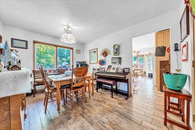 dining room featuring light wood-type flooring, a healthy amount of sunlight, and a chandelier