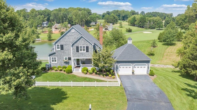 view of front of home with a front yard, a garage, and a water view