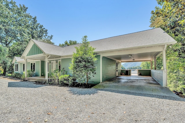 view of front of house with driveway, a shingled roof, a carport, a porch, and board and batten siding