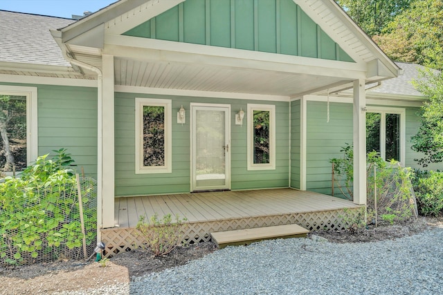 view of exterior entry with a shingled roof and board and batten siding