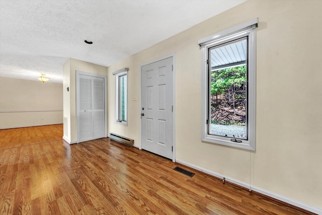 foyer entrance with plenty of natural light, a baseboard radiator, and light hardwood / wood-style floors