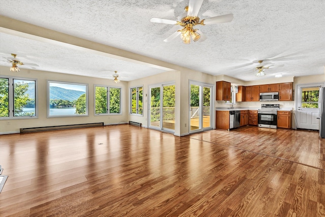 unfurnished living room featuring a baseboard heating unit, a textured ceiling, and wood-type flooring