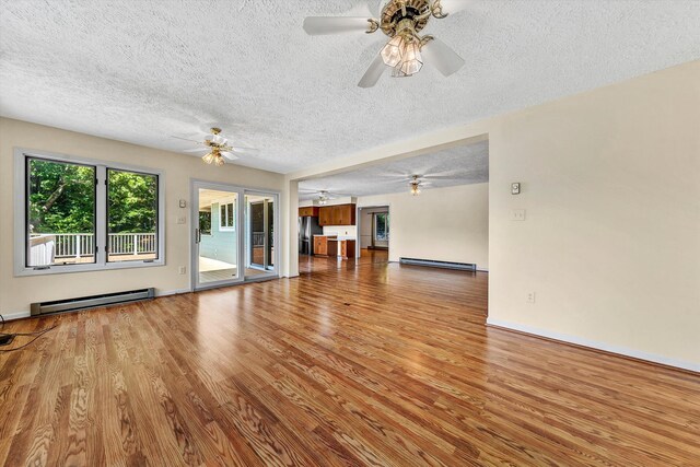 unfurnished living room with a textured ceiling, baseboard heating, hardwood / wood-style floors, and ceiling fan