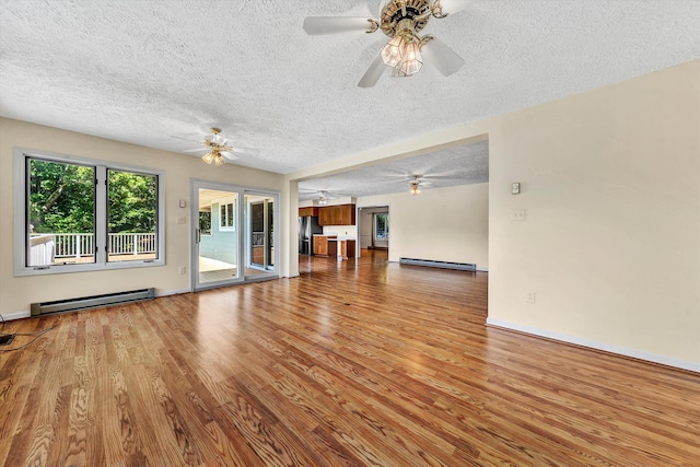 unfurnished living room with a textured ceiling, baseboard heating, and wood finished floors