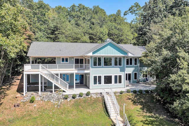 rear view of house with a yard, a patio, board and batten siding, a deck, and stairs