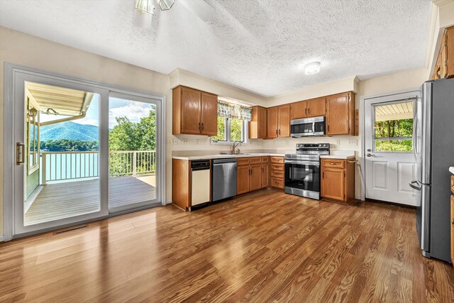 kitchen with a textured ceiling, a mountain view, stainless steel appliances, sink, and hardwood / wood-style flooring