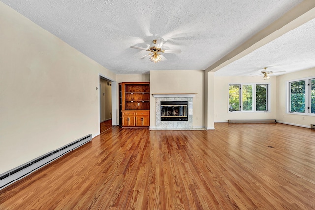 unfurnished living room with light wood-type flooring, a fireplace, baseboard heating, and ceiling fan