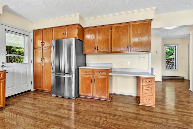 kitchen with a baseboard heating unit, freestanding refrigerator, light countertops, and brown cabinetry