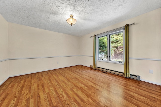 unfurnished room with a textured ceiling, baseboards, baseboard heating, and wood finished floors