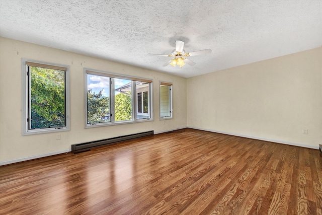 spare room with a baseboard heating unit, a healthy amount of sunlight, ceiling fan, and hardwood / wood-style floors