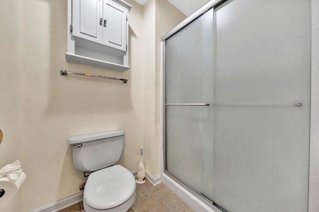 bathroom with a stall shower, baseboards, and toilet