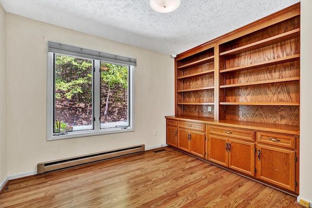 unfurnished office featuring visible vents, light wood-style flooring, a baseboard heating unit, a textured ceiling, and baseboards