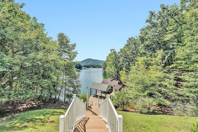 exterior space featuring a water and mountain view and a lawn