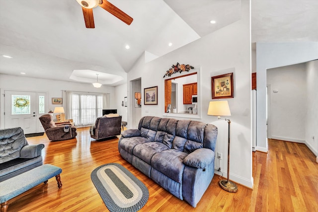 living room with vaulted ceiling, ceiling fan, and light hardwood / wood-style flooring