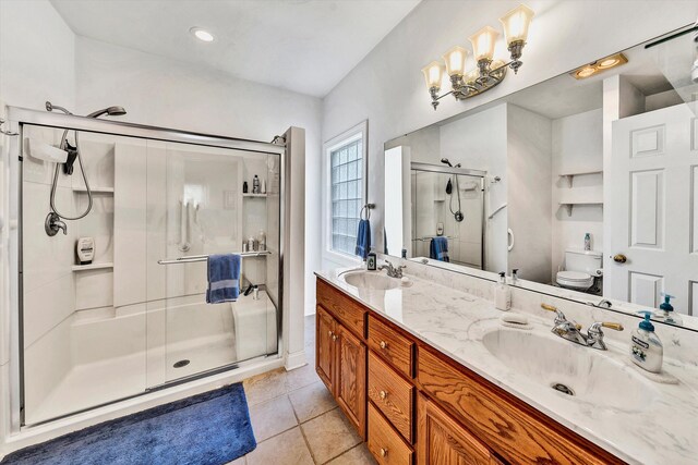 bathroom featuring vanity, toilet, a shower with door, and tile patterned floors