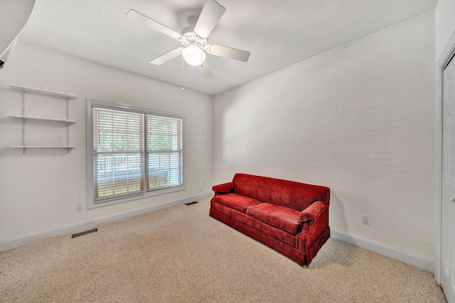 living area with light carpet and ceiling fan