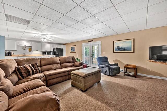 carpeted living room featuring a drop ceiling, a baseboard heating unit, ceiling fan, and sink