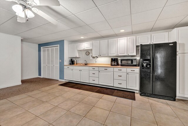 kitchen featuring ceiling fan, white cabinets, light tile patterned flooring, and black refrigerator with ice dispenser