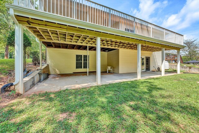 rear view of house with a lawn, a wooden deck, and a patio area