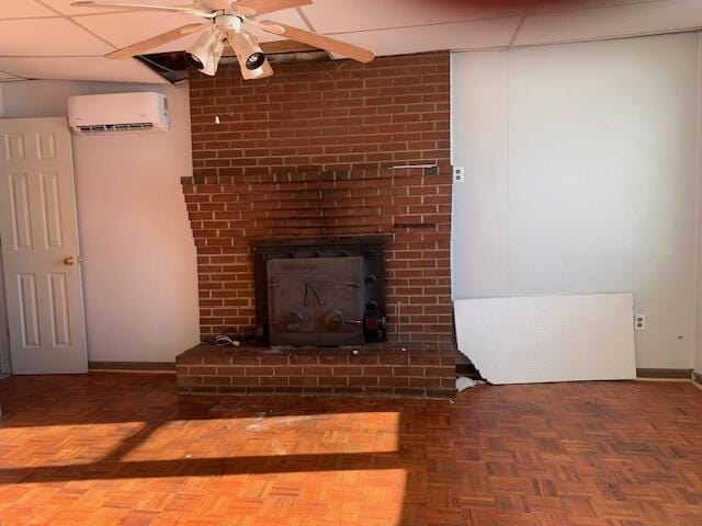 unfurnished living room featuring ceiling fan, a wall mounted air conditioner, parquet floors, and a fireplace