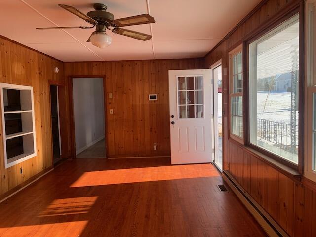 interior space with ceiling fan, baseboard heating, and a wealth of natural light