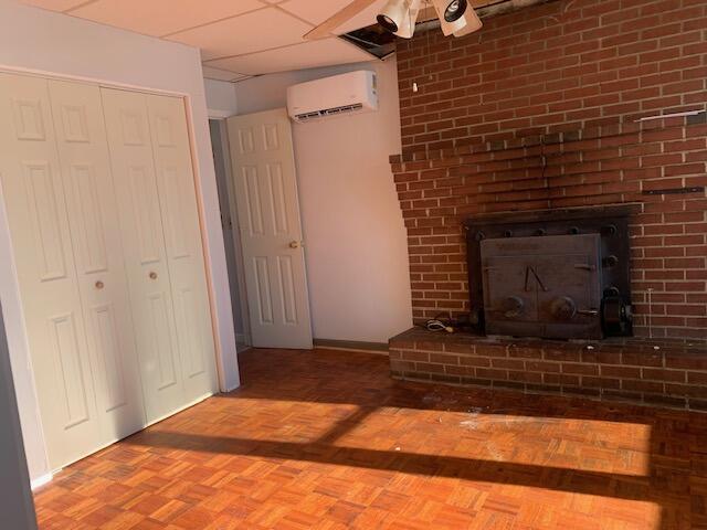 unfurnished living room featuring parquet floors and an AC wall unit