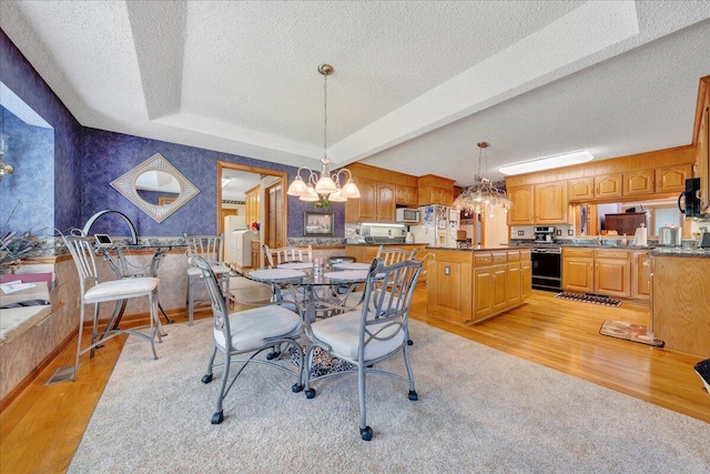 dining area with a chandelier, a tray ceiling, a textured ceiling, beamed ceiling, and light wood-type flooring