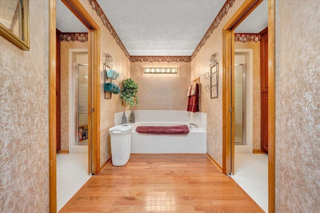 corridor featuring a textured ceiling and light hardwood / wood-style floors