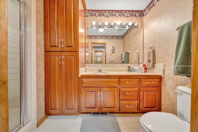 bathroom featuring vanity, a textured ceiling, tile patterned floors, toilet, and walk in shower