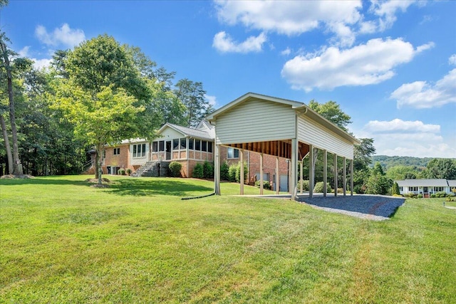 back of house with a carport, a sunroom, and a lawn