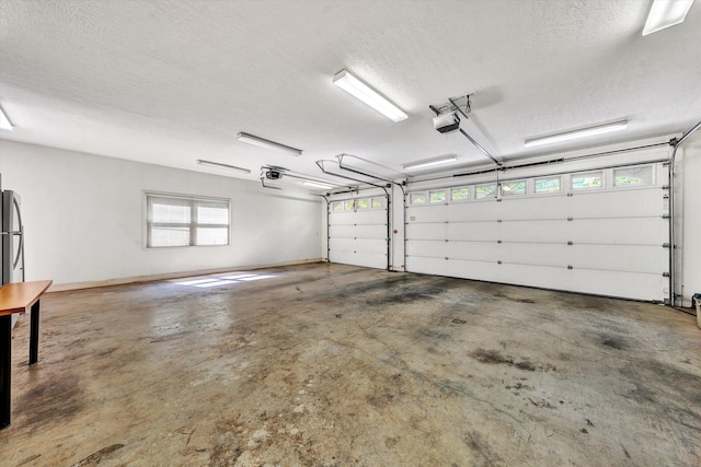 garage with a garage door opener and stainless steel refrigerator