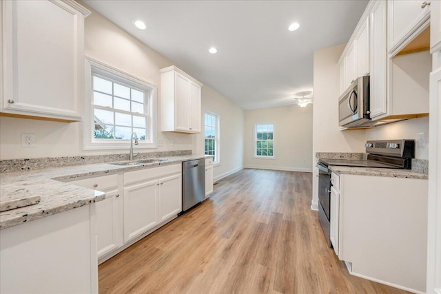 kitchen featuring recessed lighting, stainless steel appliances, a sink, white cabinets, and light wood-type flooring