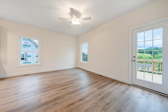 unfurnished room with visible vents, ceiling fan, light wood-style flooring, and baseboards