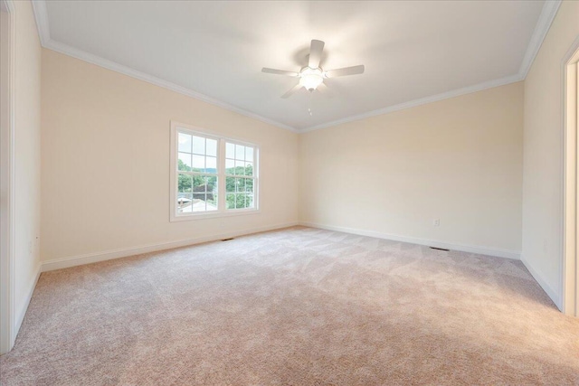 spare room featuring light carpet, ceiling fan, baseboards, and crown molding