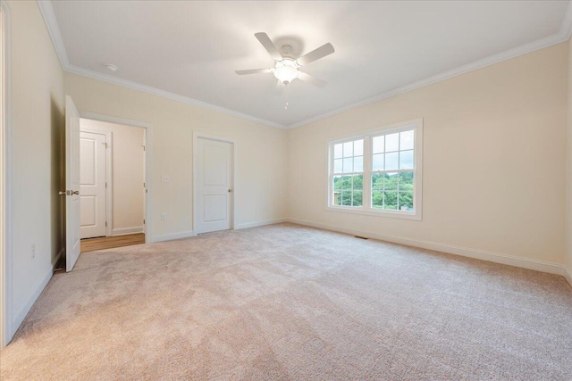 unfurnished bedroom featuring light carpet, ornamental molding, a ceiling fan, and baseboards