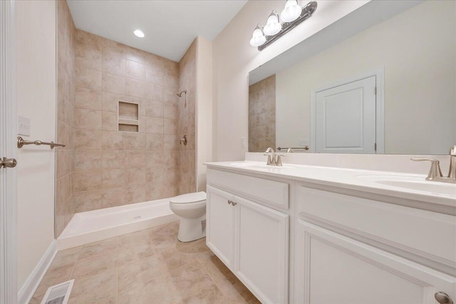 full bathroom with double vanity, visible vents, toilet, a sink, and a tile shower