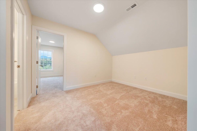 additional living space featuring lofted ceiling, baseboards, visible vents, and light colored carpet