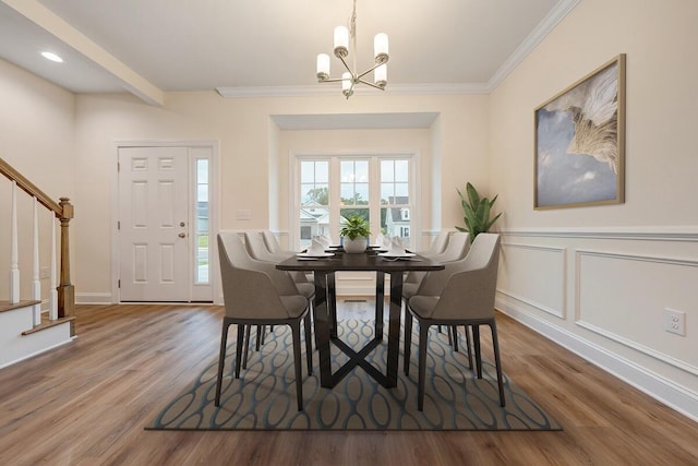 dining space with ornamental molding, stairway, wood finished floors, and a decorative wall