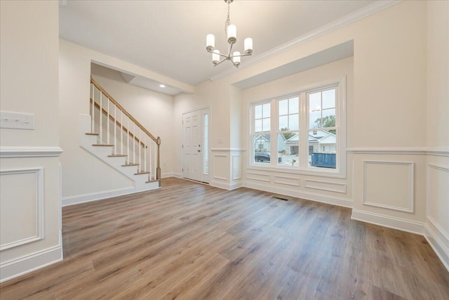 foyer with an inviting chandelier, stairs, a decorative wall, and wood finished floors