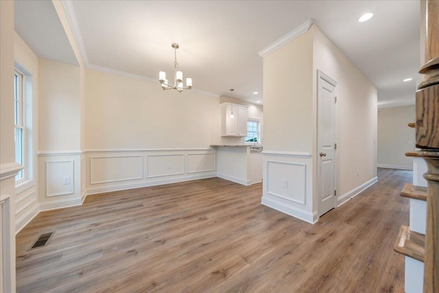 empty room with ornamental molding, light wood-type flooring, visible vents, and a notable chandelier