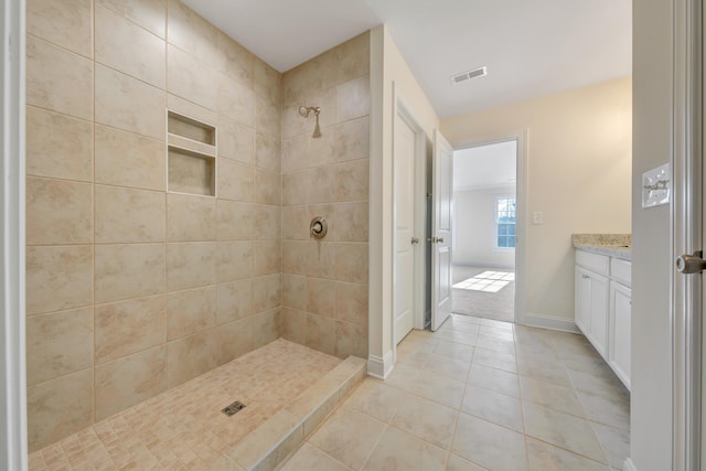 bathroom with vanity, a tile shower, and tile patterned flooring