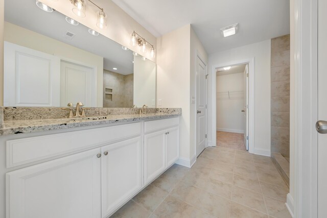 bathroom with vanity, a tile shower, and tile patterned floors